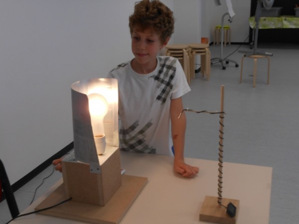 A nine years old boy is changing the brightness of a "star" (bulb) to vary the temperature at the surface of the "planet" (temperature sensor). (Photo: zvg)